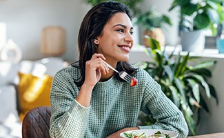 Woman smiling while eating meal at home