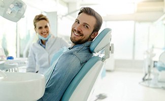 Patient smiling next to dentist while sitting in treatment chair