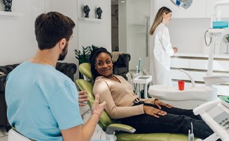 a dentist speaking with a patient sitting in a dental chair