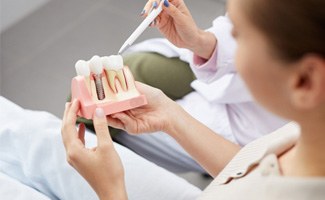 a dentist showing a patient a model of a dental implant