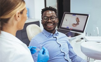 man smiling while speaking with dentist