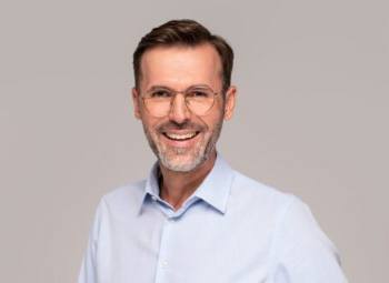 Smiling man with glasses and light blue collared shirt