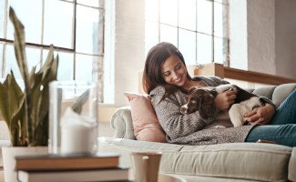 Woman smiling while relaxing on couch with her dog