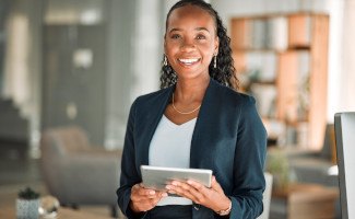 Woman smiling while holding laptop in office