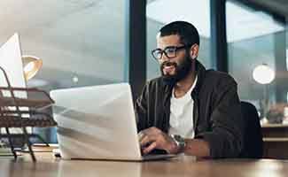 Man smiling while working on laptop in office