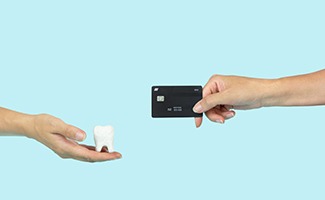 a person holding a credit card and a model tooth