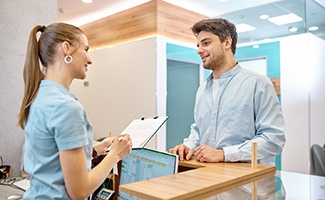 Patient and dental receptionist smiling while discussing the cost